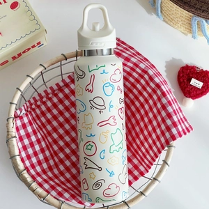Weiße Edelstahl-Trinkflasche mit bunten Kritzeleien in einem Picknickkorb