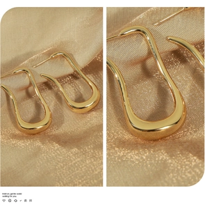 Macro shot of minimalist 18K gold-plated irregular U-shaped earrings with mirror finish