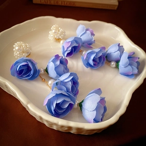 Dettaglio di orecchini a nappa lunghi con fiori di pizzo blu sfumato e perle