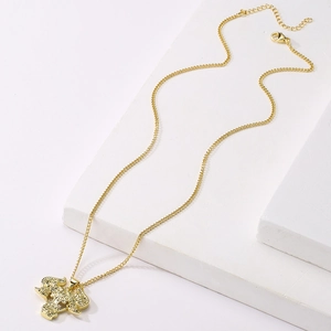Detailed view of an 18K gold plated bull head pendant necklace on a white pedestal