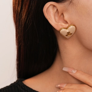 Boucles d'oreilles cœur orb élégantes en émail or et crème portées par un mannequin