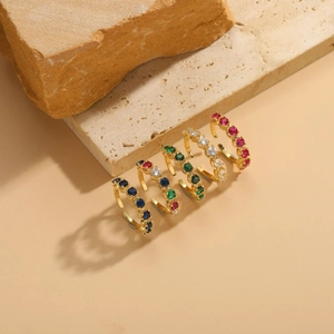 Detail of five gold plated rings with colorful zircon gemstones on a rock display