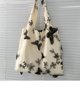 Detail of delicate black butterfly embroidery on beige mesh canvas shoulder bag