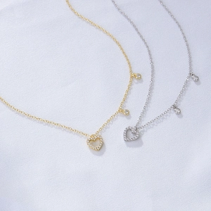 Close-up of gold and silver S925 sterling silver hollow heart necklaces on satin