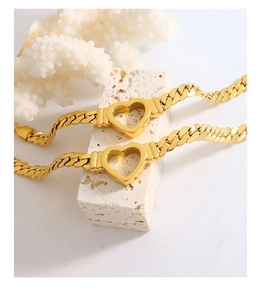 Close-up of golden stainless steel curb chain bracelet with hollow heart charms on stone