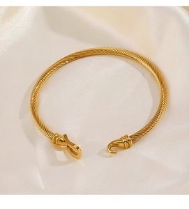 Detail of twisted cable gold bracelet with hook buckle on soft silk background