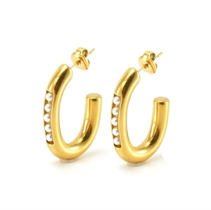 Macro view of C-shaped gold-plated hoop earrings with inlaid white pearls on white base