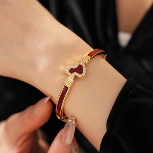 Detail eines vergoldeten Kürbis-Armbands mit roter Emaille und Zirkon am Handgelenk