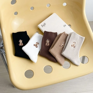 Chaussettes en coton tons terre avec broderie ours en cinq couleurs sur une chaise