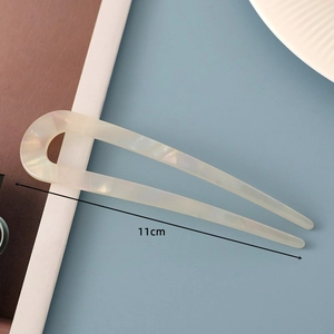Macro detail of a 11cm pearl white acetate U-shaped hair pin for minimalist hairstyles