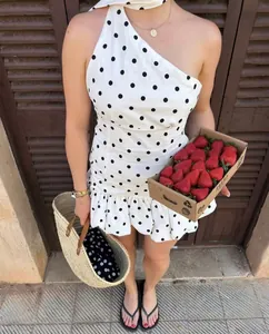 Détail d'une robe d'été blanche à pois à une épaule avec ourlet à volants et coupe slim