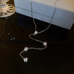 Macro shot of silver Y-shaped tassel necklace with four sparkling white crystals