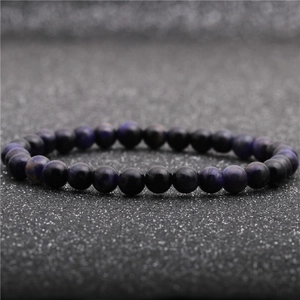 Close-up of 8mm deep purple tiger eye natural stone beads on a dark textured surface