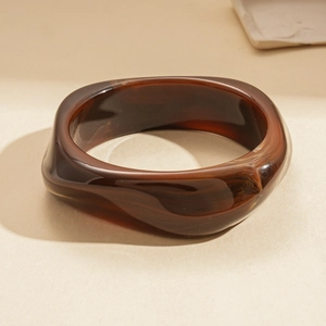 Détail montrant la texture ondulée et la résine ambre translucide du bracelet acrylique