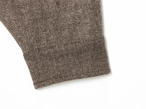 Close-up of the herringbone tweed texture and detailed cuff on the brown bomber jacket