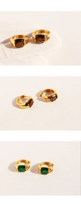 Close-up of gold hoop earrings with emerald green and brown square-cut zircons