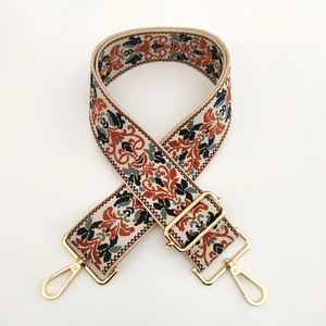 Dettaglio della tracolla larga etnica jacquard con motivi floreali e fibbie in metallo oro