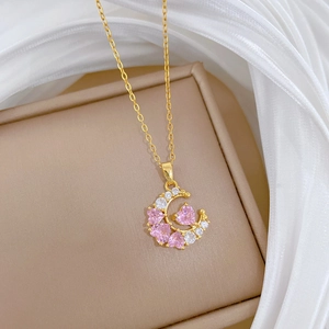 Macro shot of gold moon pendant featuring pink heart gemstone and white zircons