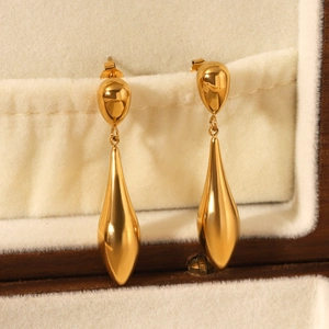 Detail of 18K gold plated teardrop earrings on a soft beige velvet jewelry display