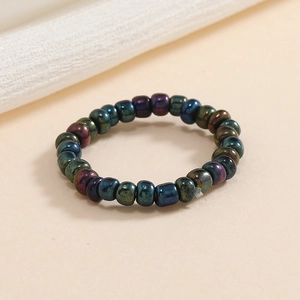 Macro di un anello elastico con perline metalliche colorate su sfondo minimalista