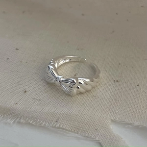 Macro view of polished 925 sterling silver bow knot ring detail on textured cloth