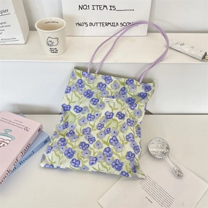 Close-up of floral tote bag with purple straps next to aesthetic home decor props