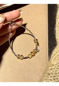 Close-up of beaded silver bracelet with yellow crystals and a single zircon charm