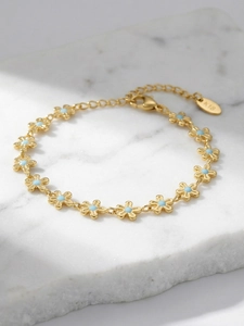 Macro shot of gold floral chain bracelet with blue enamel petals and K18 engraving