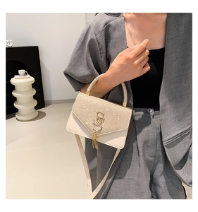 Detail of glitter shoulder bag with S-shaped metal buckle and decorative tassel detail