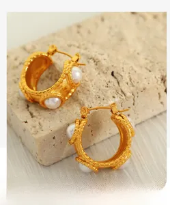 Detailed view of C-shaped 18k gold earrings with white pearl inlay and hammer texture