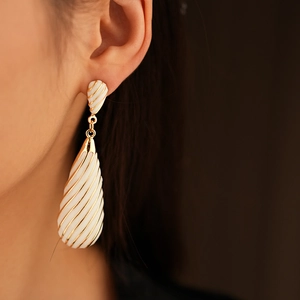 Gros plan de boucles d'oreilles vintage avec rayures en émail blanc et fini doré