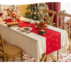 Close-up of red Christmas table runner with festive tree jacquard on a lace tablecloth