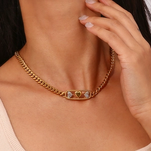 Gros plan du collier à maillons dorés avec un pendentif rectangulaire à trois cœurs