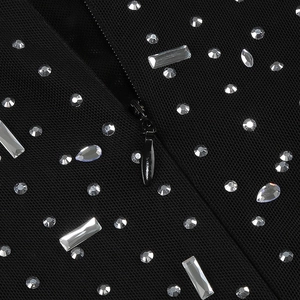 Detail of elegant black mesh dress featuring shimmering crystals and a metal zipper closure