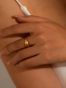 Close-up of minimalist gold titanium steel ring with wide streamlined design on index finger