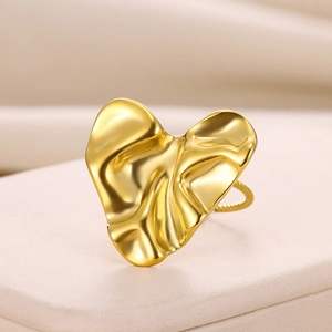 Macro detail of a gold heart ring with irregular pleated texture and twisted band