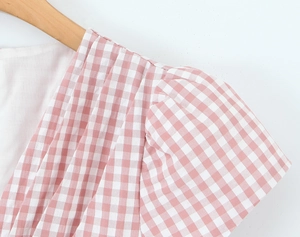 Gros plan sur la robe mini à carreaux rose et blanc avec manches bouffantes et volants