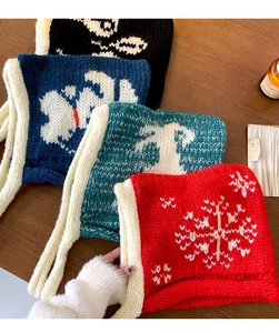 Close-up of knit balaclavas in red and blue with snowflake patterns on wood