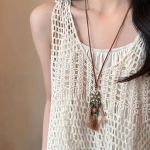 Detailed view of bohemian tassel necklace with metal flower pendant and beaded leather cord