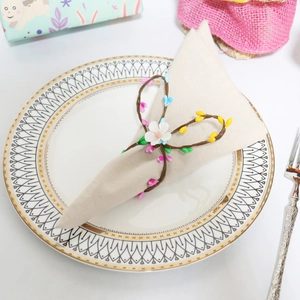 Detail of colorful berry napkin ring on beige fabric over gold-rimmed porcelain plate