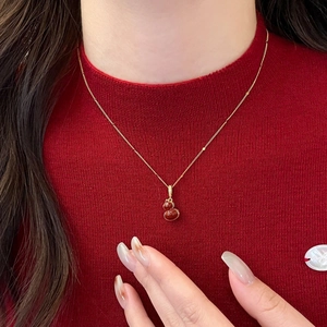 Collier gourde élégant plaqué or avec pierre rouge et zircon sur un pull rouge