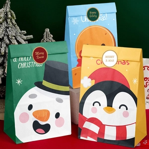 Three colorful Christmas paper gift bags with snowman and penguin designs on red background
