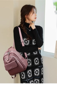 Mauve pink PU leather backpack with pebbled texture and functional zipper compartments