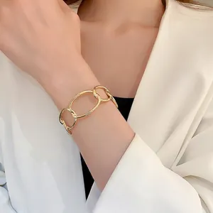 Polished gold curb chain link open bangle for women paired with elegant white suit