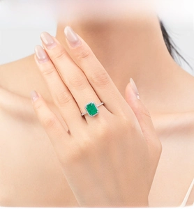 Elegant emerald cut green gemstone ring with halo setting worn on a finger