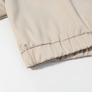 Detailed close-up of light beige jacket hem with elasticated ribbed texture and clean seams