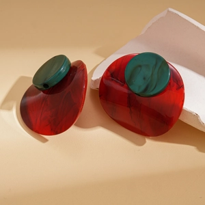 Detail of red and green acrylic earrings with marble texture on minimalist props