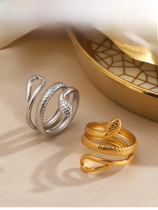 Close-up of gold and silver snake rings with textured scales on a decorative dish