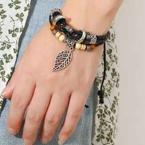 Macro detail of multi-layer beaded leather bracelet with silver leaf pendant on wrist