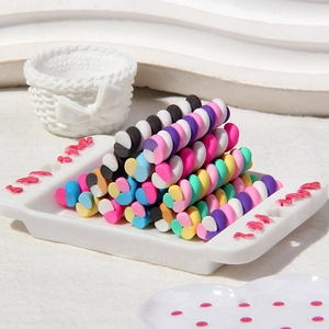 Colorful spiral polymer clay canes for DIY phone cases stacked on a white ceramic tray